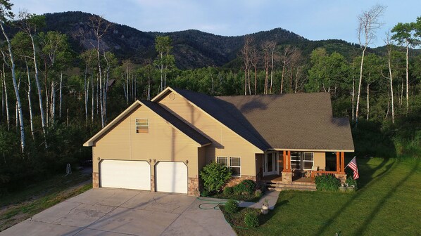 A single-story house with a garage, surrounded by a well-maintained lawn and tall trees. - Family Lodge in Beautiful Star Valley (Star Valley Ranch)