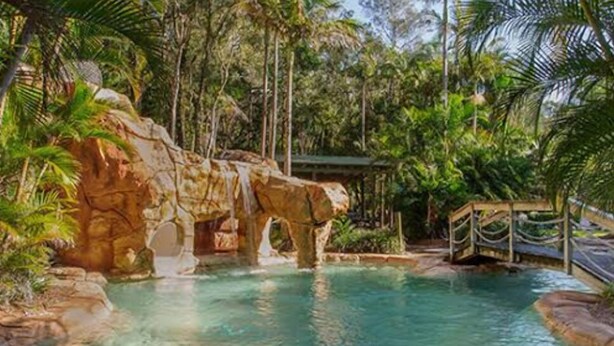 Un área de piscina con una formación rocosa y un puente de madera.