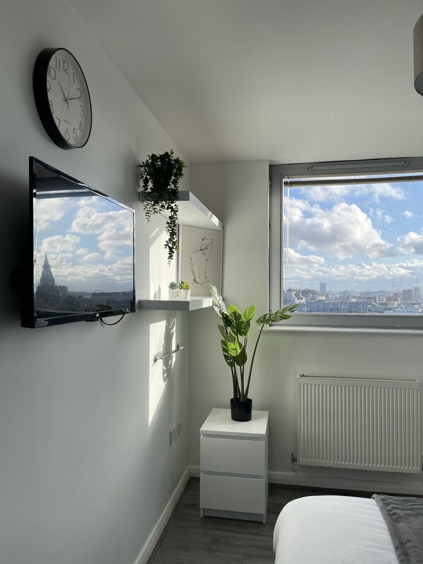Enjoy a city view from the large window in this stylish bedroom with a mounted TV and a cozy reading nook.