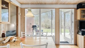 Une cuisine moderne avec des meubles en bois, une table à manger avec des chaises et une grande fenêtre donnant sur un jardin.