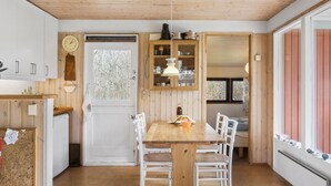 Une cuisine chaleureuse avec une table en bois, des chaises blanches et un buffet rempli de vaisselle.
