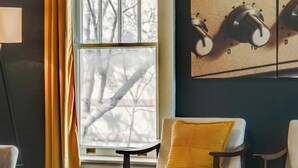 A room with a large window, a painting, and two chairs with yellow cushions. - Sleeps 8 Historic loft near 12 South with easy access to local attractions (Nashville)