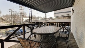 A covered outdoor patio with a round table and chairs, a view of the street, and a building in the background. - Sleeps 8 Historic loft near 12 South with easy access to local attractions (Nashville)