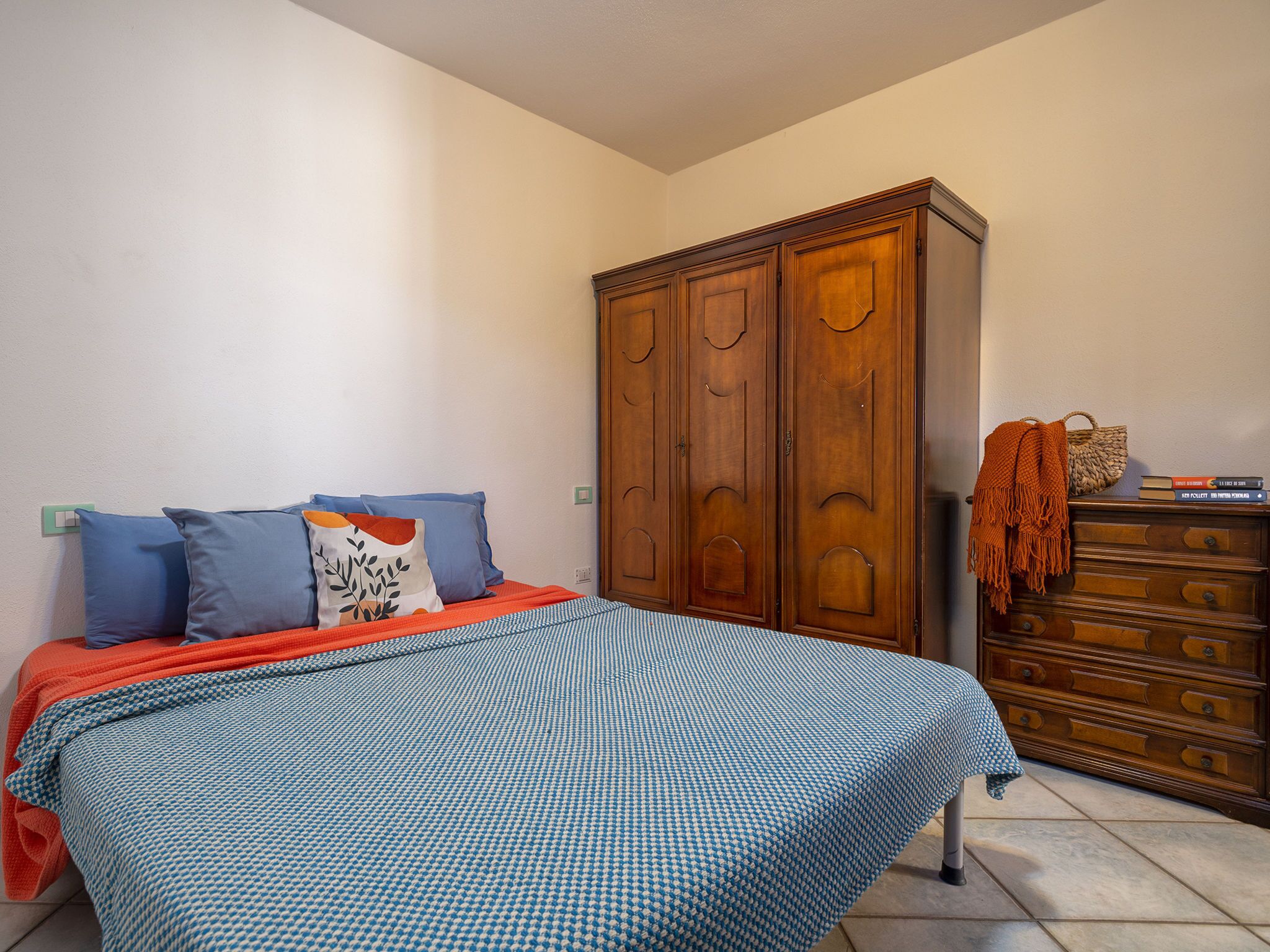 A bedroom with a bed, pillows, a dresser, and a wardrobe.