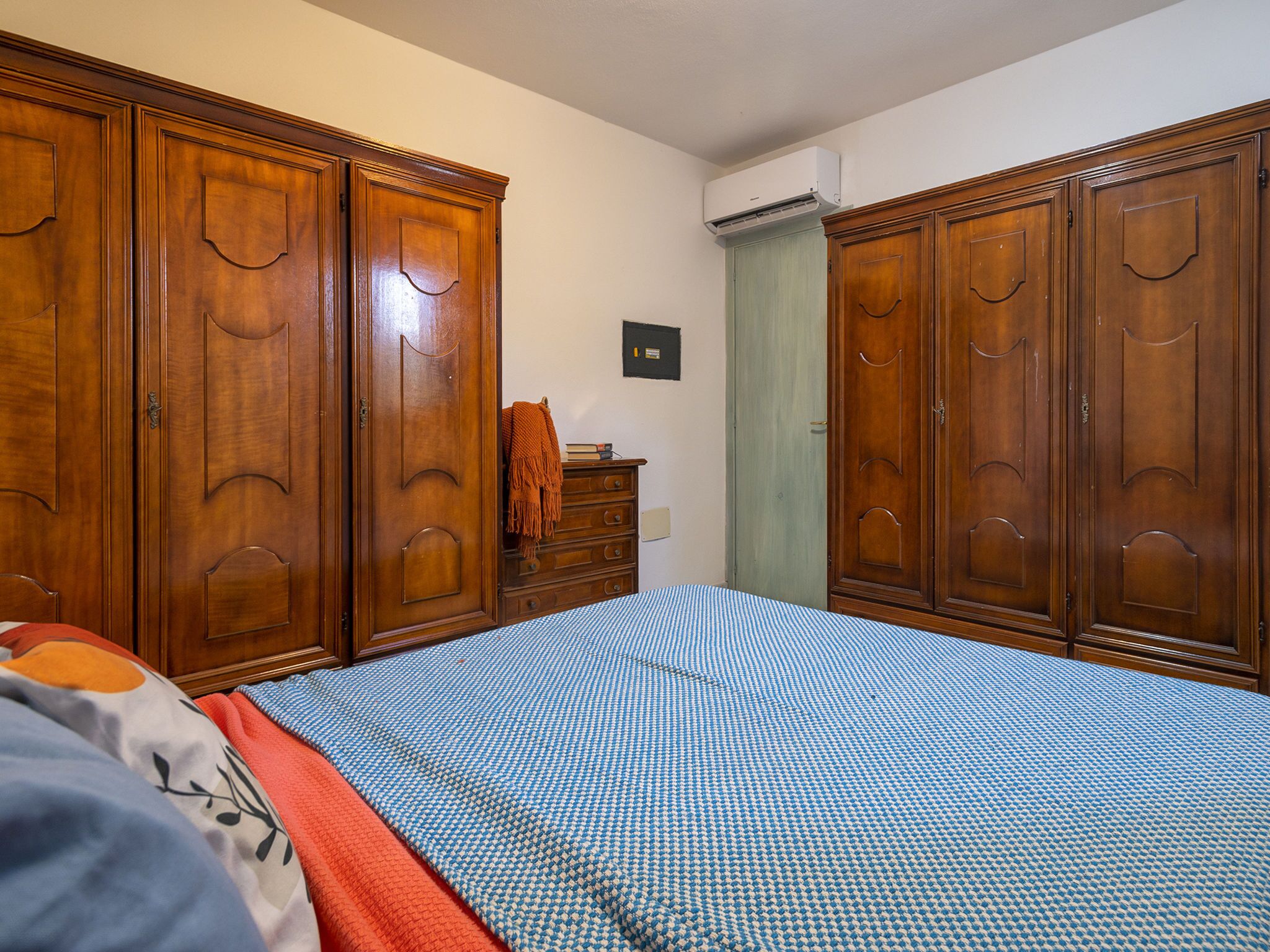 Un dormitorio con una cama grande, un armario de madera y un aparador.