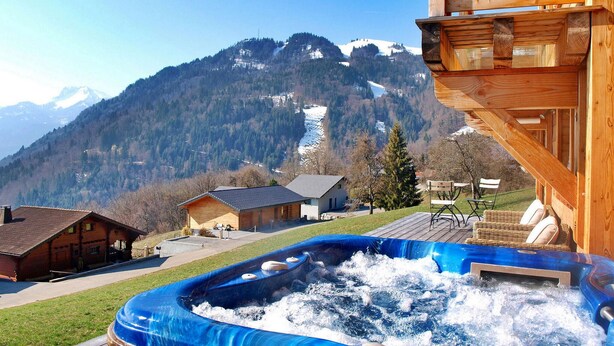 A hot tub with a wooden deck, a wooden cabin, and a mountain view in the background. - Gorgeous home in Onnion with WiFi (Onnion)