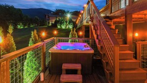Una vasca idromassaggio su un pontile in legno, con una scalinata che conduce a un edificio.