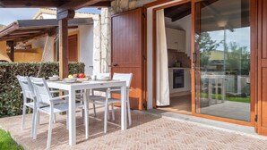 A patio with a table and chairs, a stone wall, and a sliding glass door leading to a kitchen. - Vacation home Momo by Interhome (Valledoria)