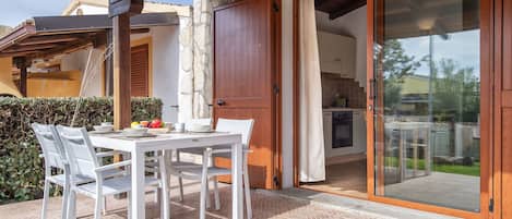 A patio with a table and chairs, a stone wall, and a sliding glass door leading to a kitchen.