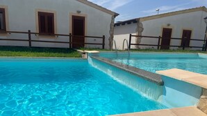 A swimming pool with clear blue water, surrounded by stone walls and wooden doors. - Vacation home Momo by Interhome (Valledoria)
