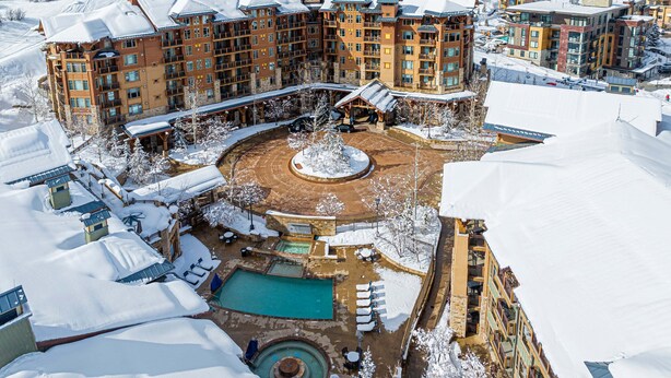 A snow-covered resort with multiple buildings, a central pool area, and a ski lift in the background. - Luxury Amenities in Canyons!  Ski-in/Ski-out, Amenities, In-room dining (Park City)