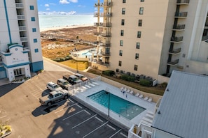 Un hotel moderno con piscina en la azotea, estacionamiento y vistas a la playa.