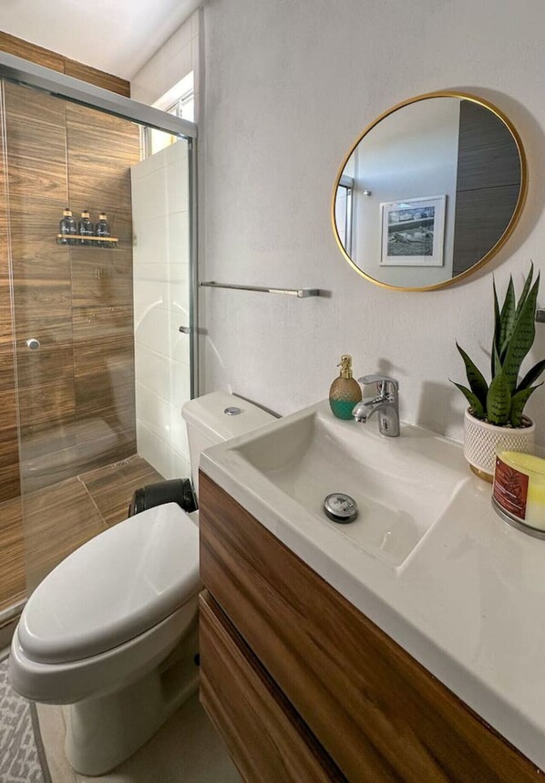Un baño moderno con inodoro, lavamanos y ducha.