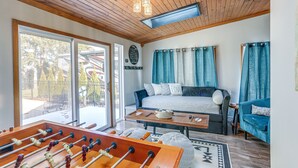 Una sala de estar acogedora con una mesa de fútbol de mesa, un sofá y una cama con cortinas azules.