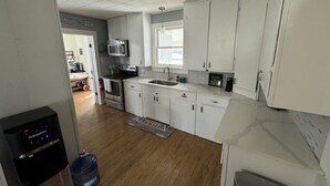 A modern kitchen with white cabinets, stainless steel appliances, and a water dispenser. - Cozy Retreat in Geronimo w/ 2 BD (Seguin)