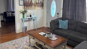 A living room with a ceiling fan, a cityscape painting, a sofa, and a coffee table. - Cozy Retreat in Geronimo w/ 2 BD (Seguin)
