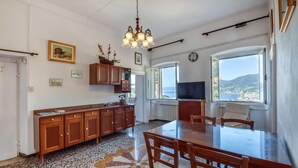 Une cuisine spacieuse avec une grande table à manger, des meubles de rangement en bois et une vue sur la mer grâce à une grande fenêtre.