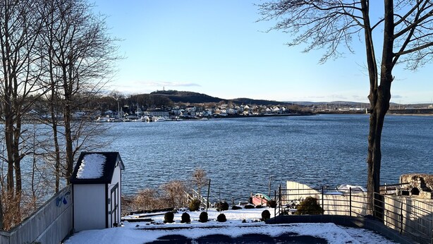 A snowy landscape with a view of a body of water and a distant town.