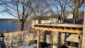 A backyard with a wooden pergola, outdoor seating, and a grill area.