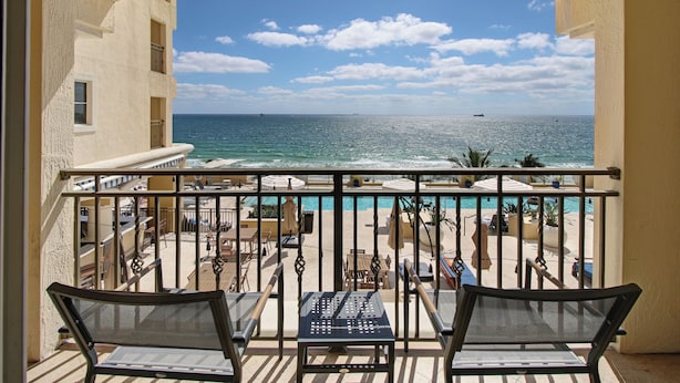 Un balcon avec vue sur l’océan, un espace salon extérieur et une zone piscine.
