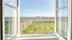 Ein Fenster mit Blick auf eine Wiese und eine entfernte Küste.