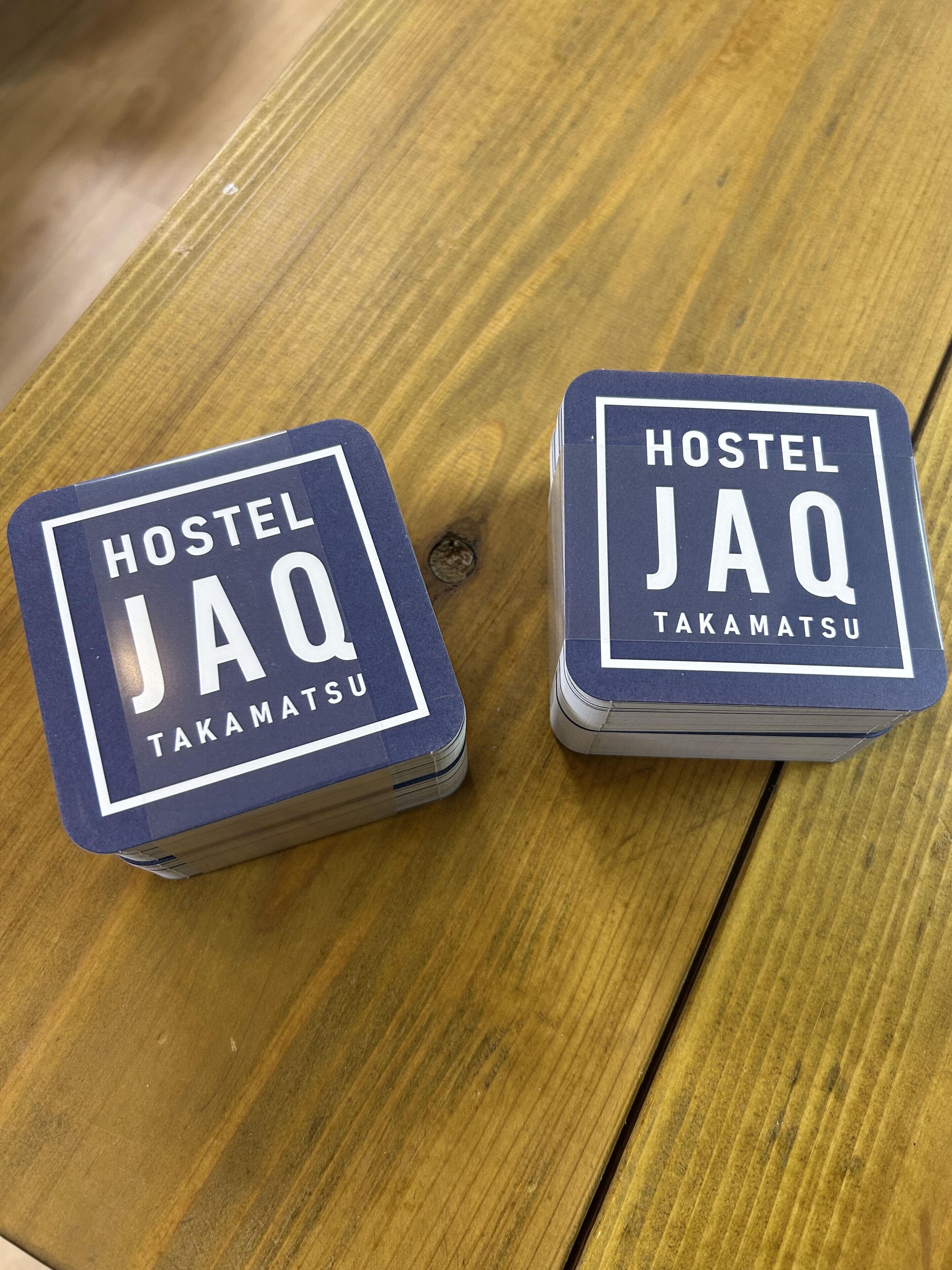 Dos contenedores azules y blancos con la marca Hostel JaQ sobre una mesa de madera.