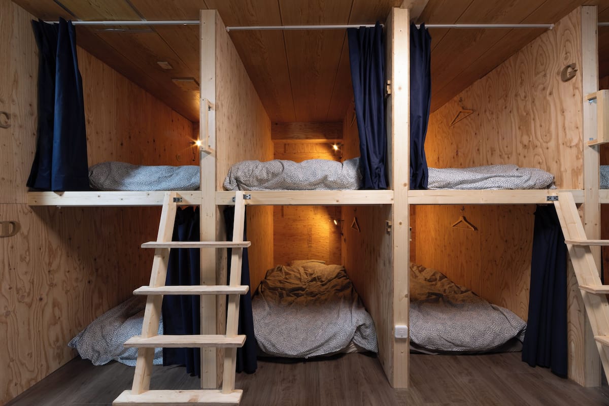 Een houten blokhut met stapelbedden, een ladder en een hanglamp.