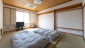 A traditional Japanese room with tatami flooring, a futon bed, a television, and sliding doors. - Hostel JAQ takamatsu (Takamatsu)