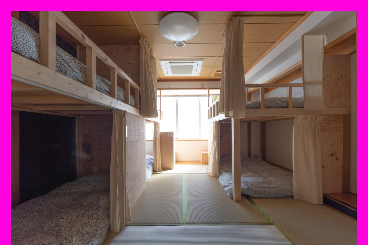 Een slaapkamer met stapelbedden, een centrale doorgang, houten wanden en een plafondventilator.