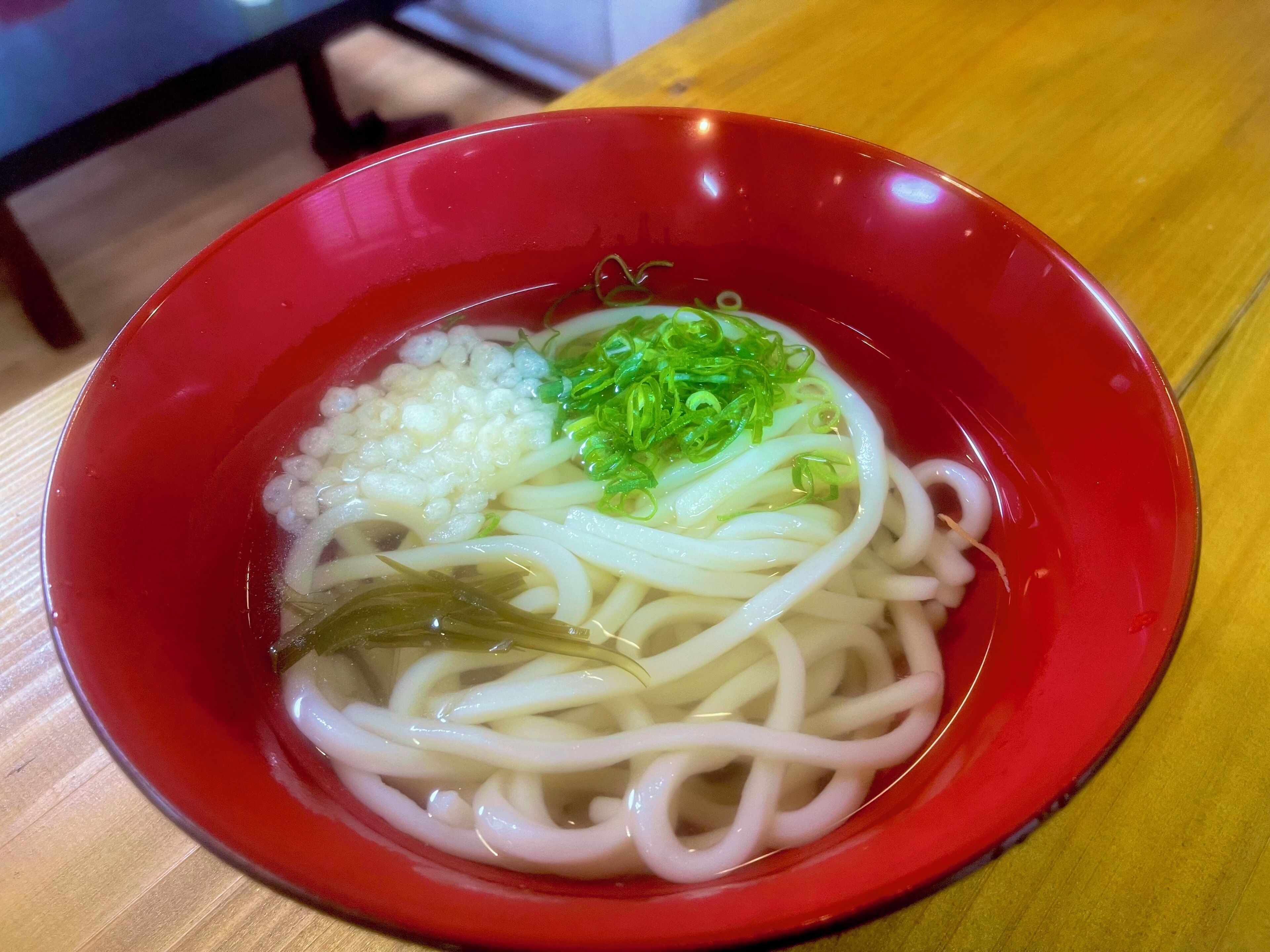 Un tazón de fideos con ingredientes, sobre una mesa de madera.