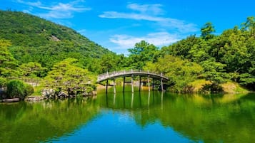 A serene landscape with a wooden bridge over a calm lake, surrounded by lush greenery and hills.