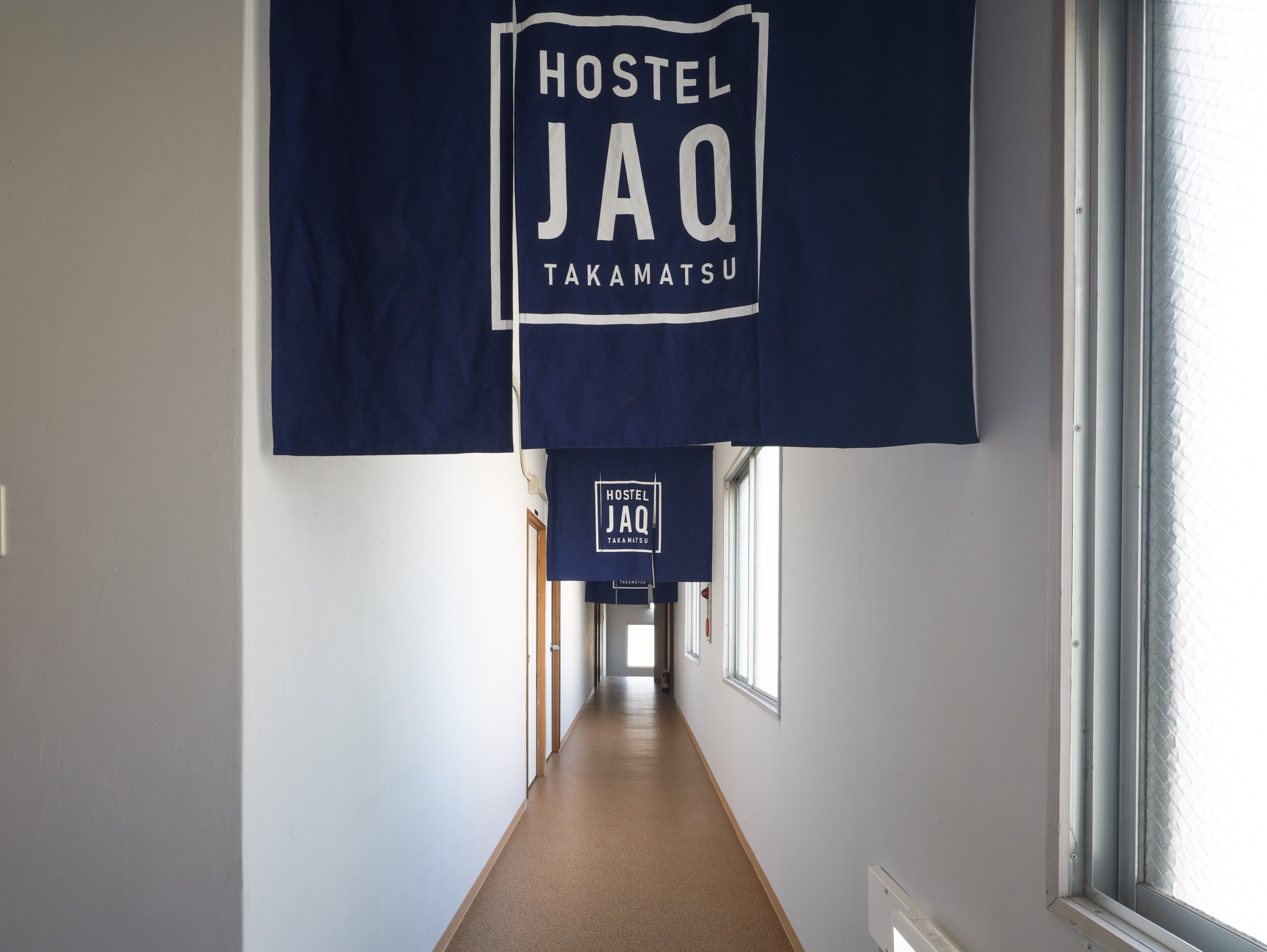 A hallway with a sign reading "Hostel JAQ Takamatsu".