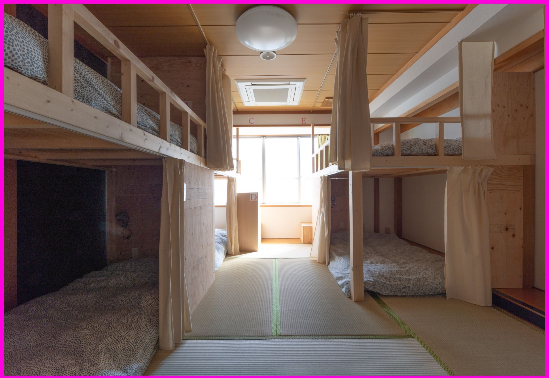 A bunk bed room with a central walkway, wooden walls, and a ceiling fan.