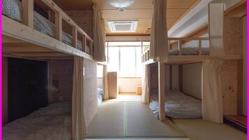 A bunk bed room with a central walkway, wooden walls, and a ceiling fan.