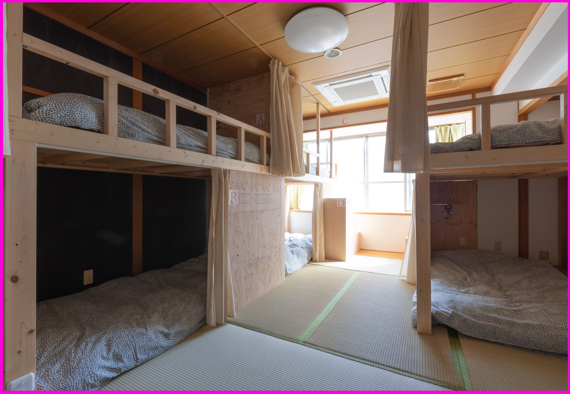 A dormitory room with bunk beds, tatami mats, and a ceiling fan.