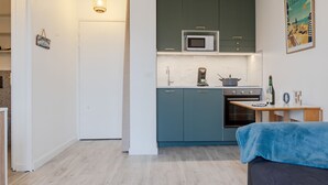 Kompakti keittiö, jossa on turkoosinsiniset kaapit, mikroaaltouuni, kahvinkeitin ja pieni uuni.