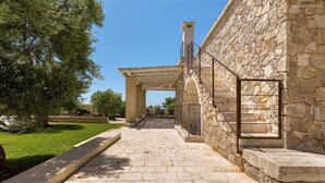 A stone pathway leading to a stone building with a covered entrance and a metal staircase. - 1159 Perla Bianca by Perle di Puglia (Ugento)