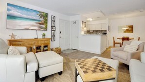 Ein Wohnzimmer mit einer Couch, einem Couchtisch und einem Bild von einer Strandlandschaft.