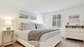 Ein Schlafzimmer mit einem Bett, Nachttischen, einer Kommode und Kunstwerken an den Wänden.