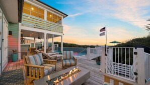 A deck with outdoor seating, a fire feature, and a view of the ocean at sunset. - PELICAN PLACE: Gulf Front 75ft Private Beach! Pool + Hot Tub! Elevator, Outdoor Kitchen, Green Egg (Inlet Beach)