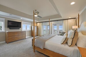 Relax in a spacious bedroom with a large bed, four-poster headboard, and a dresser with multiple drawers.