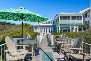 Relax in the serene outdoor seating area with a clear view of the house, surrounded by lush greenery and a blue sky.
