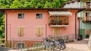 Um edifício com fachada rosa, persianas de madeira e varanda com grades de metal.