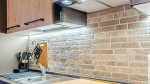 Uma cozinha moderna com painel de tijolos, tábua de corte de madeira e pia de aço inoxidável.