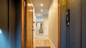 A hallway with wooden doors, a carpeted floor, and a light-colored wall.