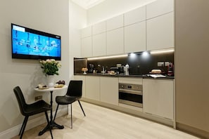 Enjoy meals in the kitchen with an oven and flat-screen TV, plus a dining area with two chairs and a table.