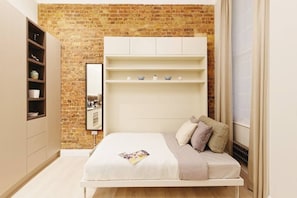 Cozy retreat with a brick accent wall, white bed, and wardrobe.