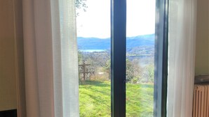 Een kamer met een groot raam dat uitzicht biedt op een groen landschap en verre bergen.