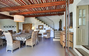 A spacious living area with a high ceiling, a staircase, wicker furniture, and a statue.