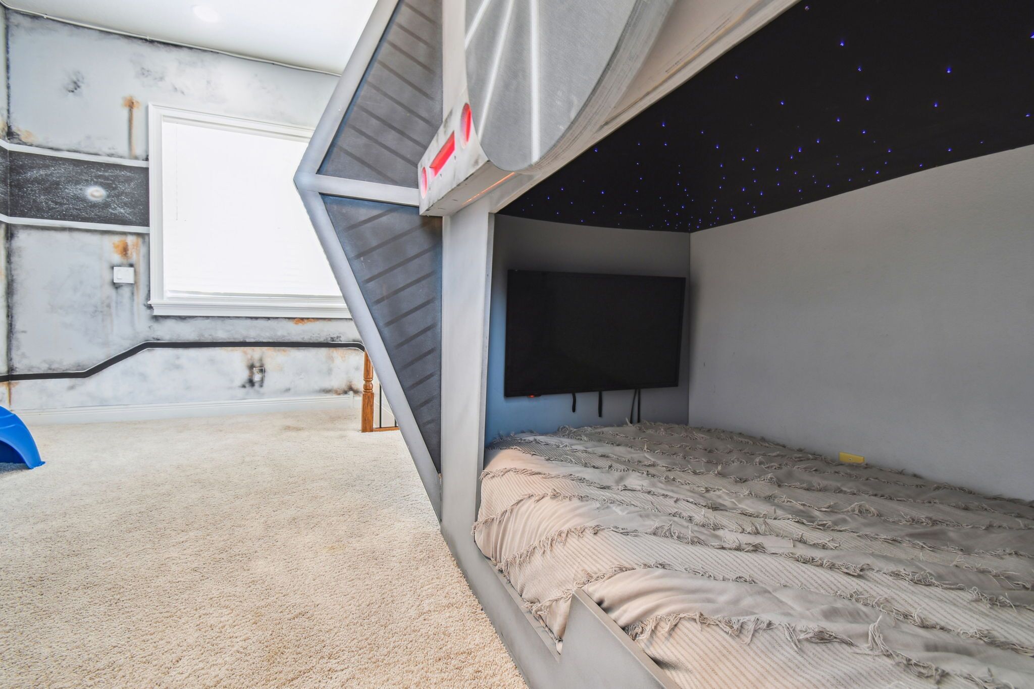Quarto com cama, televisão e teto estrelado.